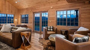 A spacious room with wooden walls and large windows, furnished with leather sofas and a central coffee table. - EML 6 Hidey-Hole (Paonia)