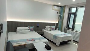 A hotel room with two beds, a small table, a bench, an air conditioning unit, a window, and a radiator. - Xi'an Terracotta Warriors and Horses Xingqin Inn (Xi'an)