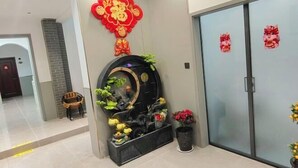 A reception area with a traditional red Chinese decoration, a black circular water feature, and potted plants. - Xi'an Terracotta Warriors and Horses Xingqin Inn (Xi'an)