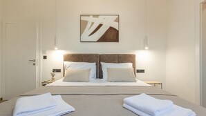 Ein Hotelzimmer mit einem großen Bett, zwei Nachttischen, einem Wandbild und einer Tür.