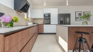 Eine moderne Küche mit Holzschränken, Edelstahlgeräten und einer Kochinsel.