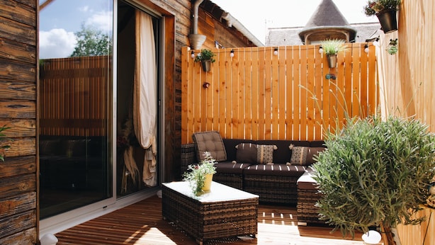 A wooden deck with a sofa and coffee table, a wooden fence, and potted plants. - Maison Cosy I Terrasse Privée (Nemours)