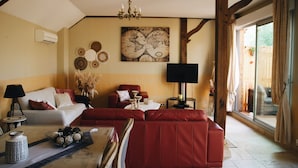 A spacious living room with a red sofa, a white sofa, and a coffee table with decorative items. There is a large world map on the wall and a television on a stand. - Maison Cosy I Terrasse Privée (Nemours)