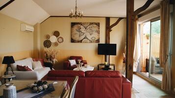 Un vaste salon comprenant un canapé rouge, un canapé blanc et une table basse agrémentée d’objets décoratifs. Un grand planisphère est accroché au mur, et un téléviseur est posé sur un meuble.
