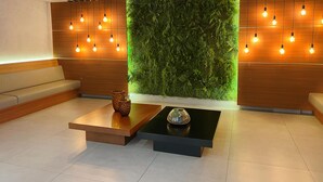 Eine moderne Lobby mit grüner Wand, Holzvertäfelung und einer Sitzecke.