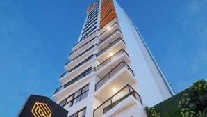 Ein modernes Hochhaus mit einem auffälligen Logo und der Aufschrift "ECO FIT RESIDENCE" auf einem Schild.