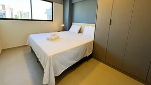 Ein Hotelzimmer mit Bett, Stadtblick durch ein Fenster und einem Kleiderschrank.