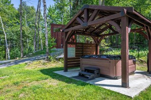 A wooden gazebo with a hot tub, surrounded by a natural forest setting. - Luxury Adventure Cabin Kayaks, Trails, Lakes Hot Tub (Cavendish)