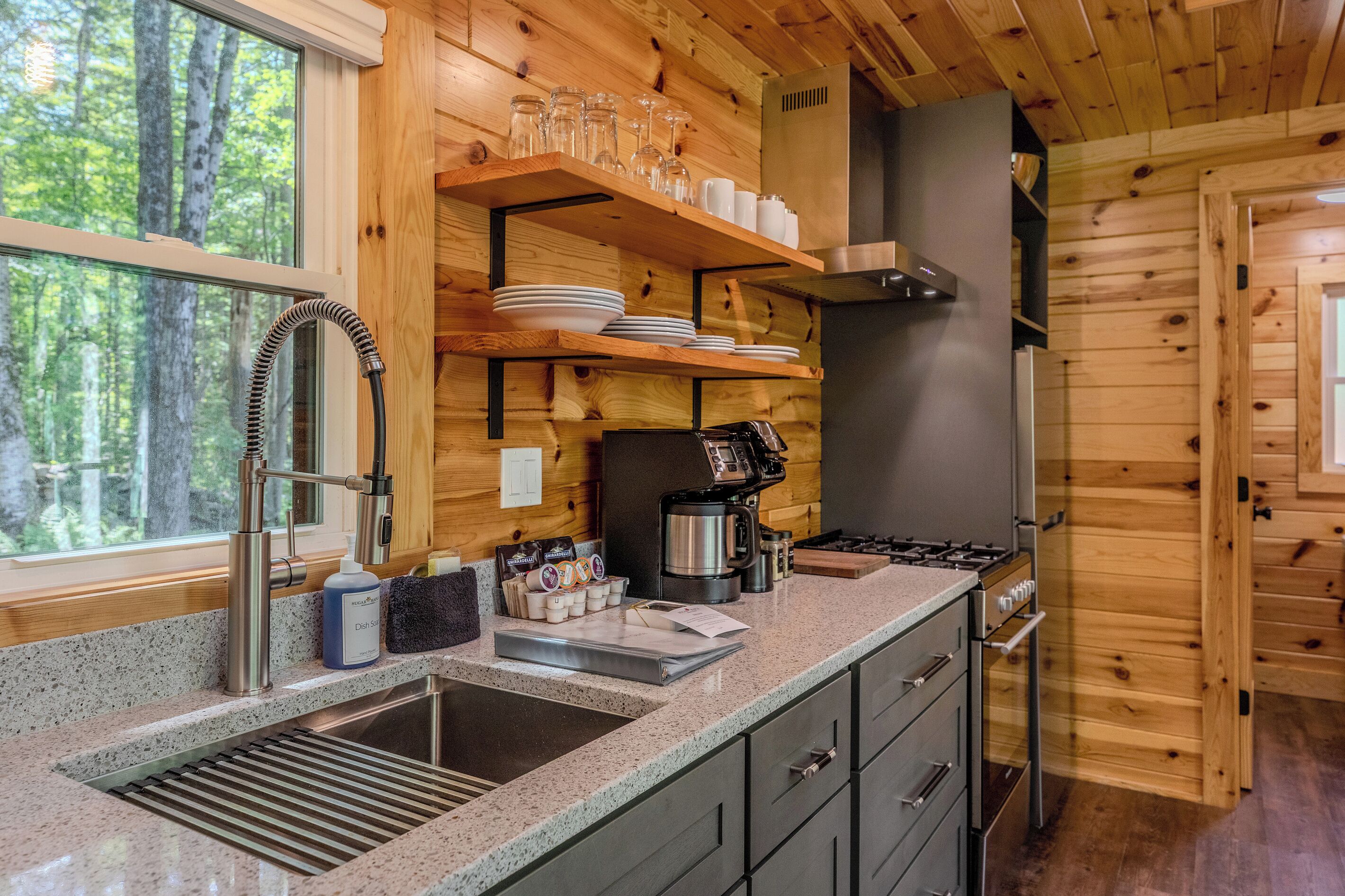 A kitchen with wooden walls, a stainless steel sink, and a coffee maker.
