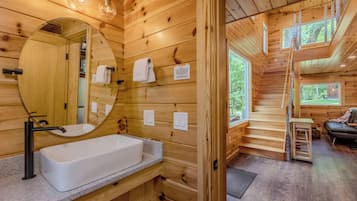 Ein Holzblockhaus-Interieur mit Badezimmer, das ein Waschbecken, einen Spiegel und einen Handtuchhalter zeigt.