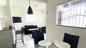 Un espace repas moderne avec une table en verre, des chaises noires et des sets de table blancs.