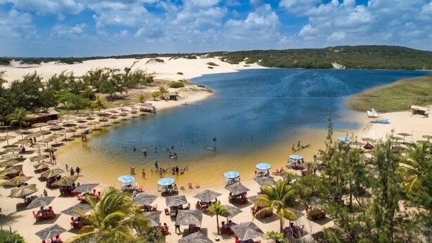 Un complexe hôtelier de bord de mer doté d’une grande piscine, de nombreux parasols et de chaises de plage.