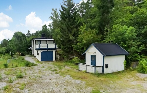 Two small, single-story buildings with a simple, functional design, surrounded by dense greenery and a clear sky.