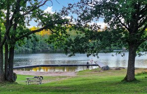 A lakeside park with a picnic table and a dock extending into the water.