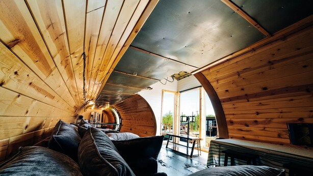 A cozy interior with wooden walls, a curved ceiling, a sofa, and a bench. - Iconic 727 Jet: Private Aft Suite + Lounge (Houston)