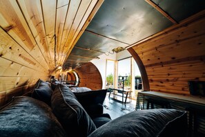 Ein gemütliches Interieur mit Holzwänden, einer gewölbten Decke, einer Couch und einer Bank.