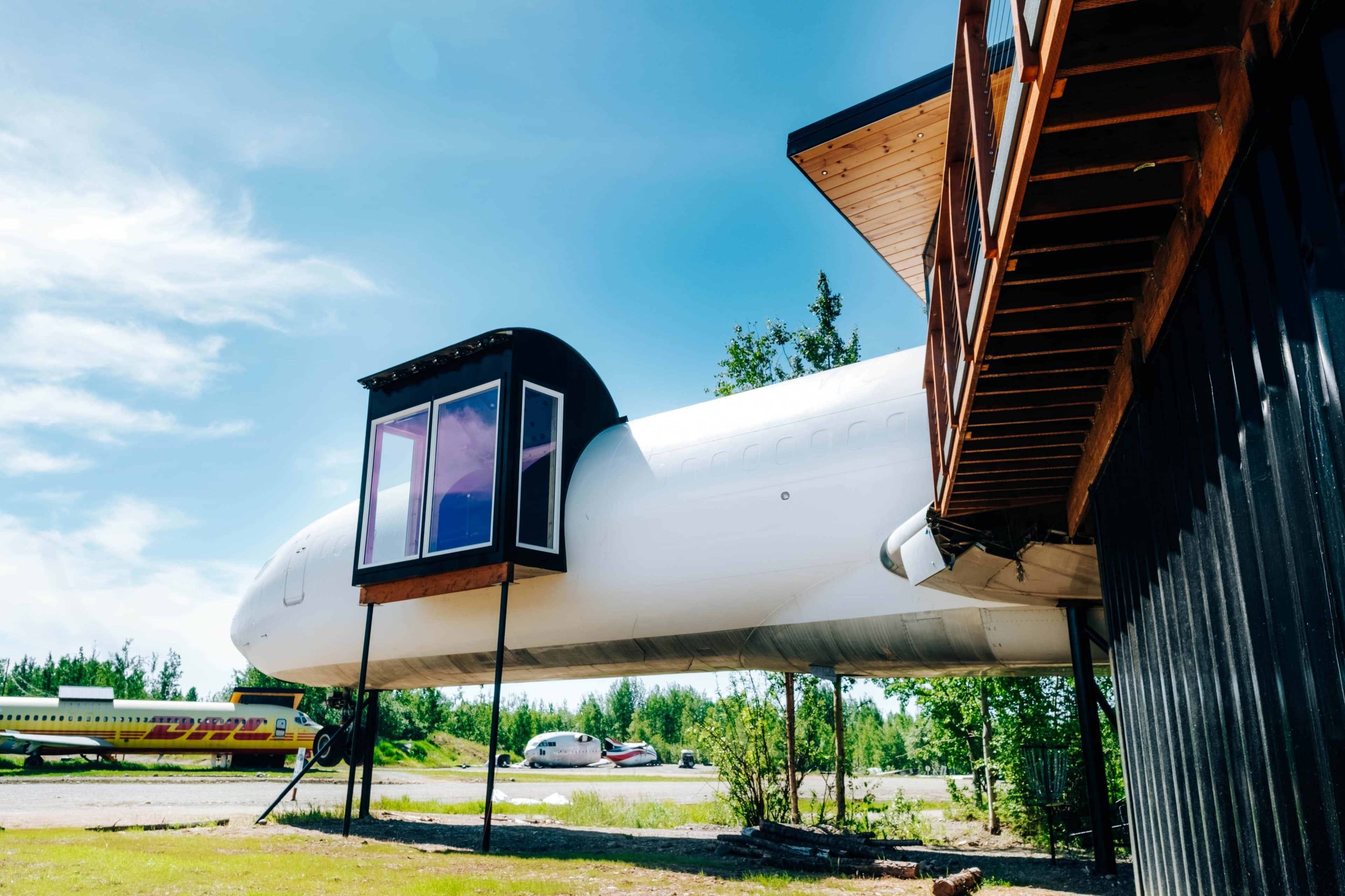 Un grand avion doté d’un petit habitacle, un bâtiment avec un toit en pente et un ciel dégagé.
