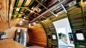 A kitchen with a stainless steel refrigerator, wooden walls, and a curved ceiling. - Iconic 727 Jet: Private Aft Suite + Lounge (Houston)