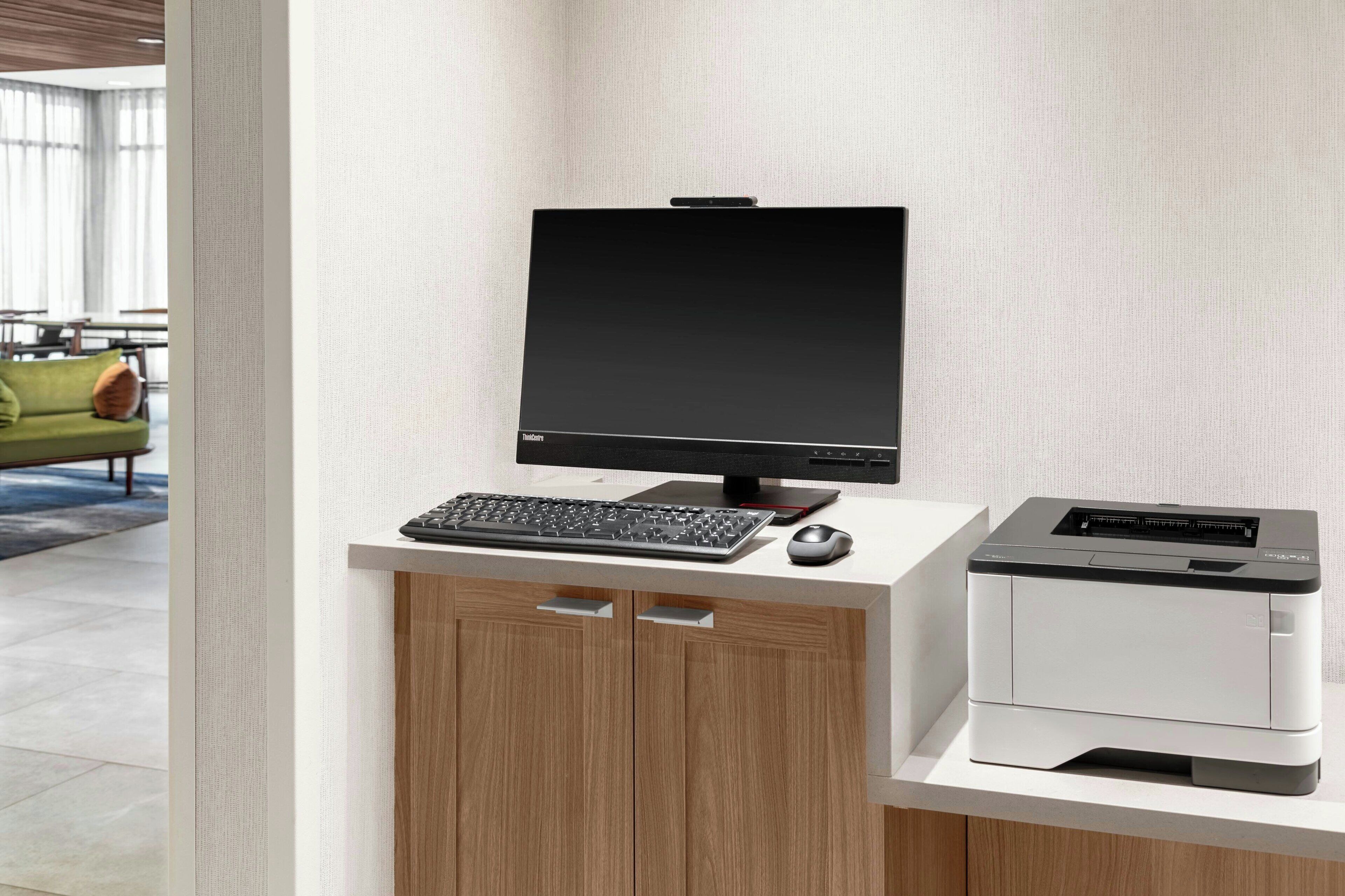 A modern office desk with a desktop computer, keyboard, mouse, and a printer.