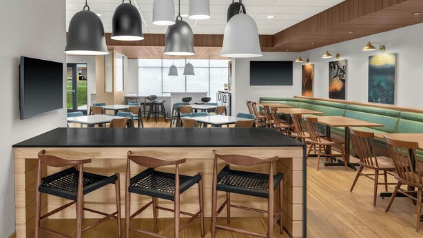 A modern restaurant with a central bar area, multiple seating options including booths and tables, and pendant lighting. -  Fairfield Inn & Suites by Marriott® Norwalk Des Moines (Norwalk)