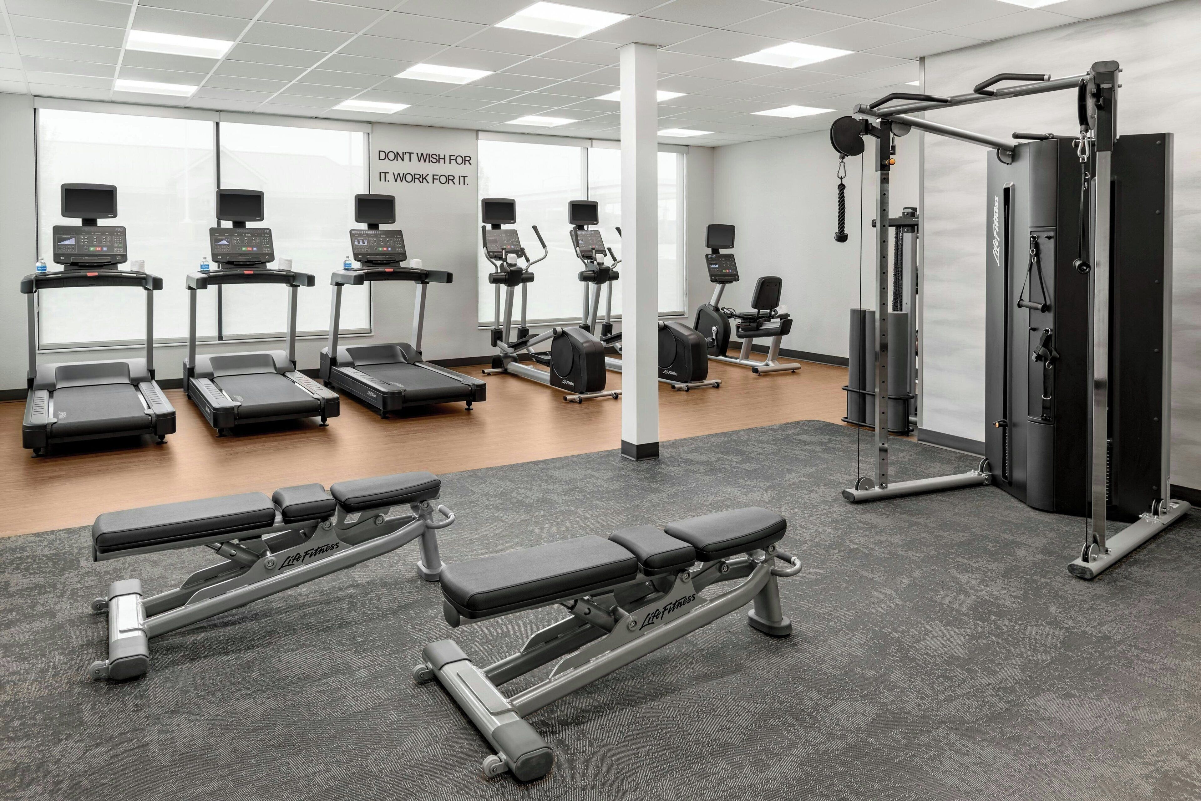 A gym with treadmills, elliptical machines, and weightlifting equipment.