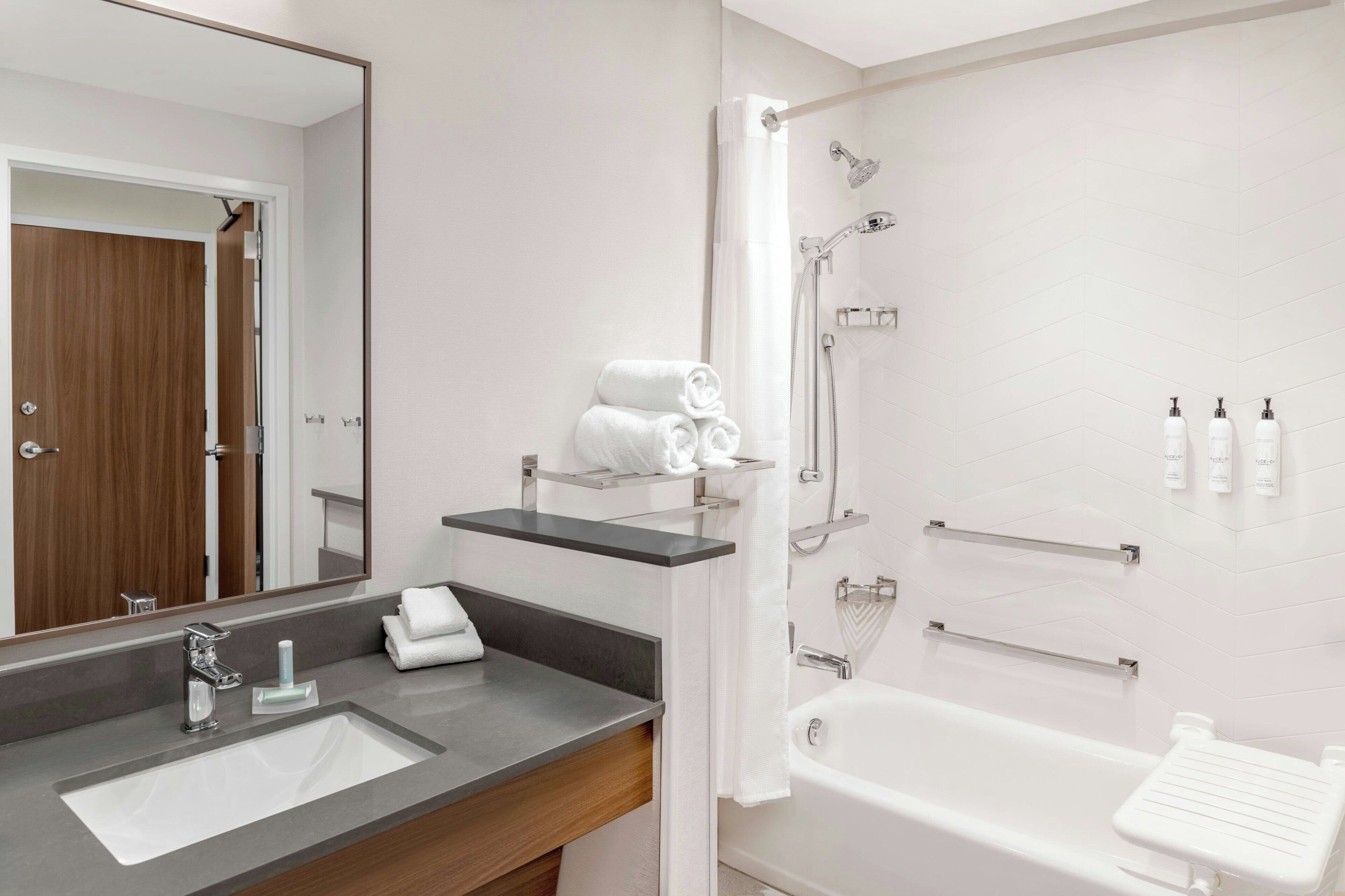 Een moderne badkamer met een grote spiegel, een wastafel, een bad en een douche.