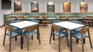 A restaurant with green booths, wooden tables, and blue chairs.