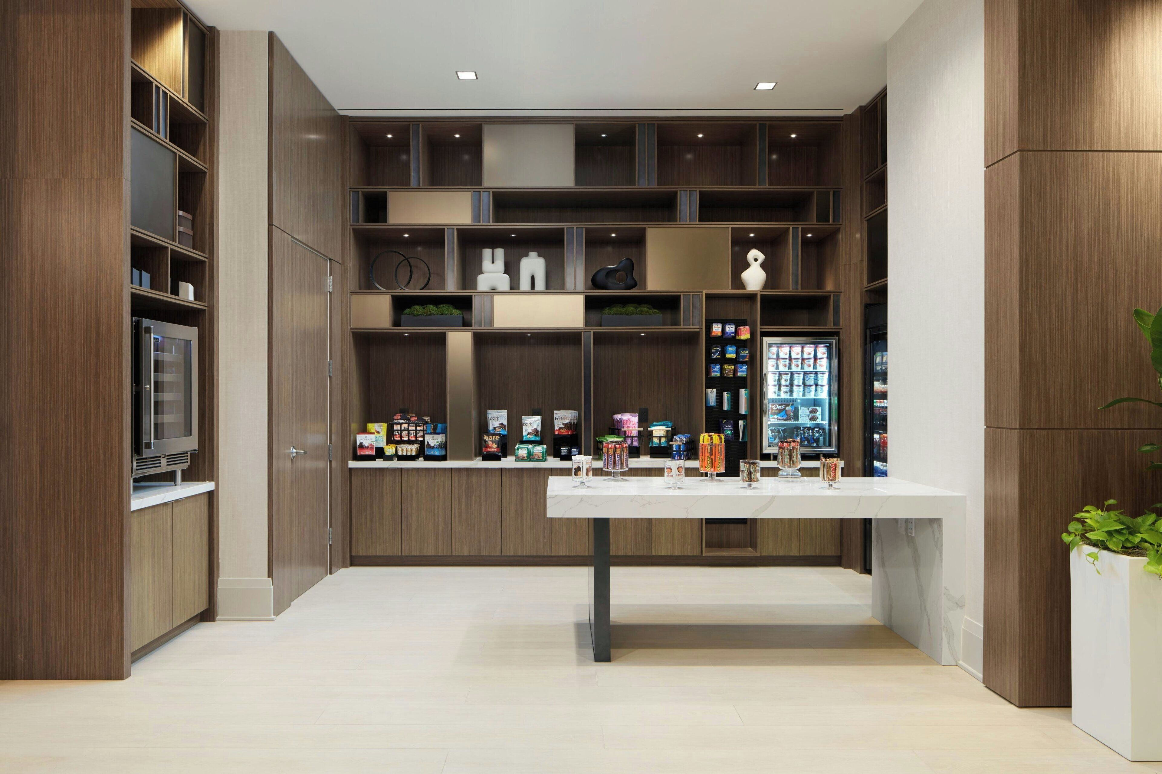 A modern kitchen with built-in wooden cabinets, a marble countertop, and various kitchen appliances.