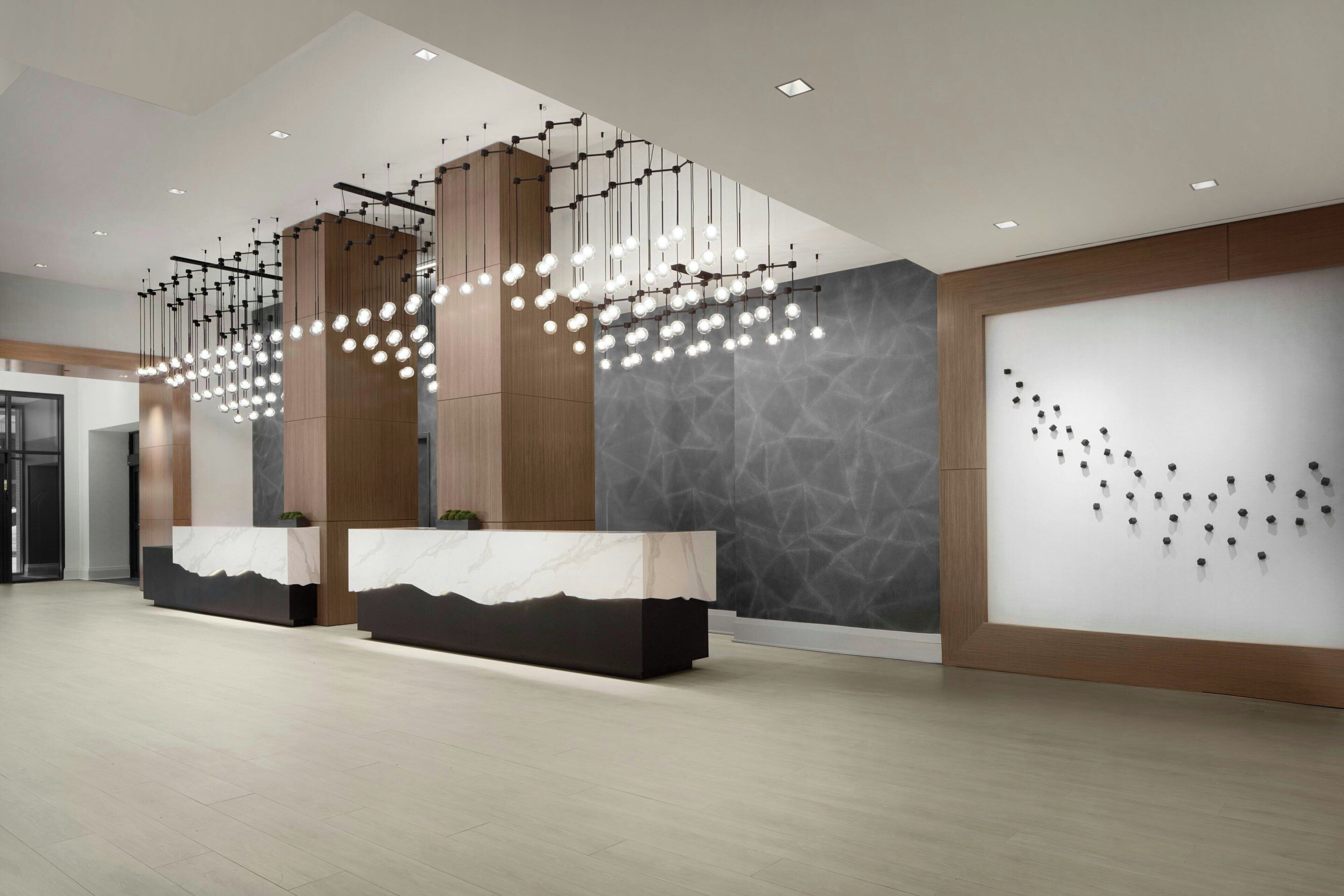 A modern reception area with marble counters, hanging pendant lights, and a textured wall.