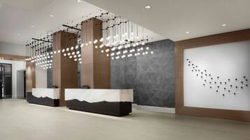 A modern reception area with marble counters, hanging pendant lights, and a textured wall.