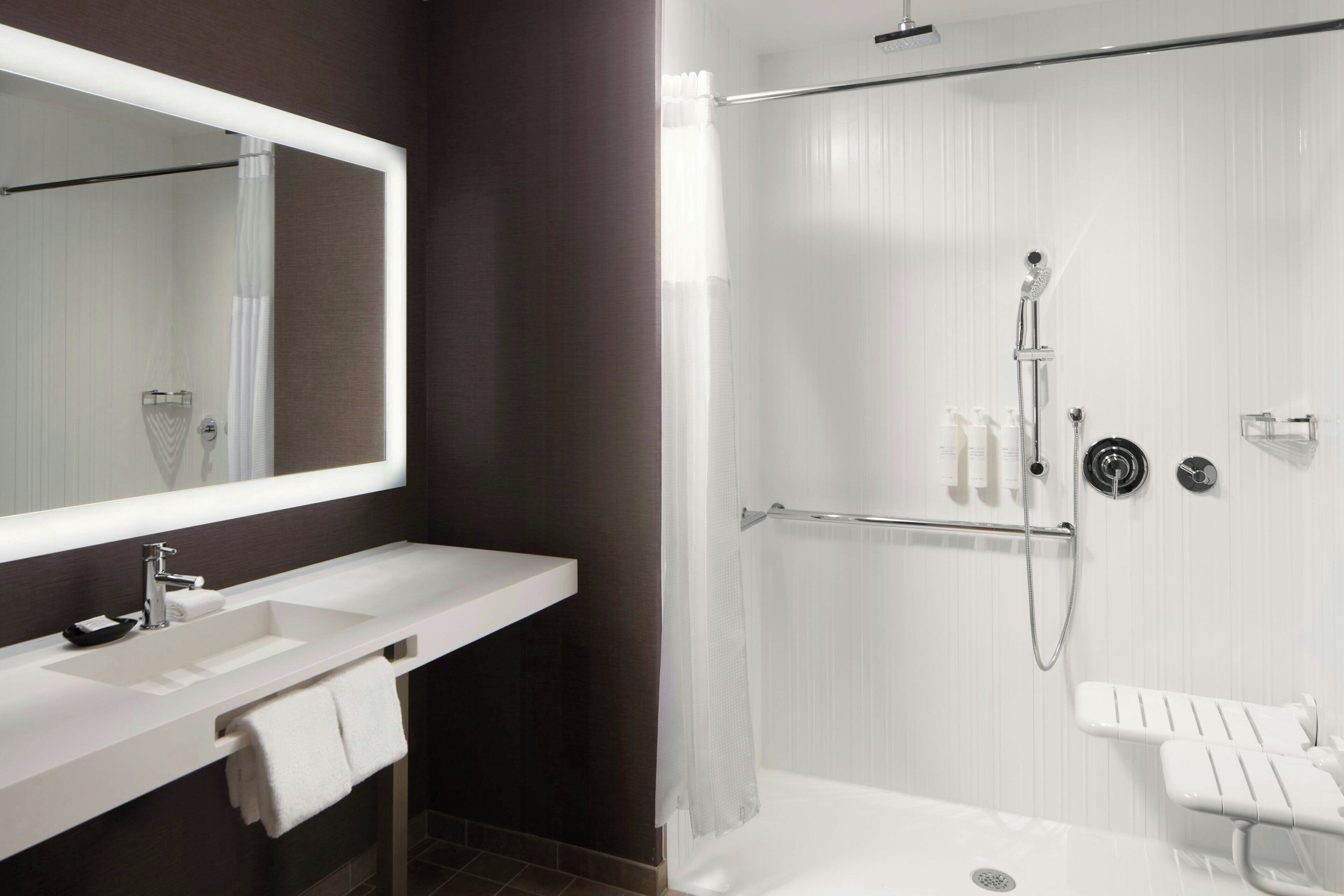 A modern bathroom with a white sink, mirror, and shower area.
