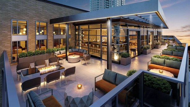 Un espacio lounge exterior moderno con asientos, bar y una chimenea.
