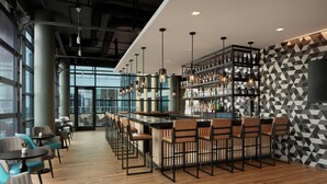 Un espace bar moderne doté d’un long comptoir, de nombreux tabourets et d’un mur orné d’un motif géométrique.