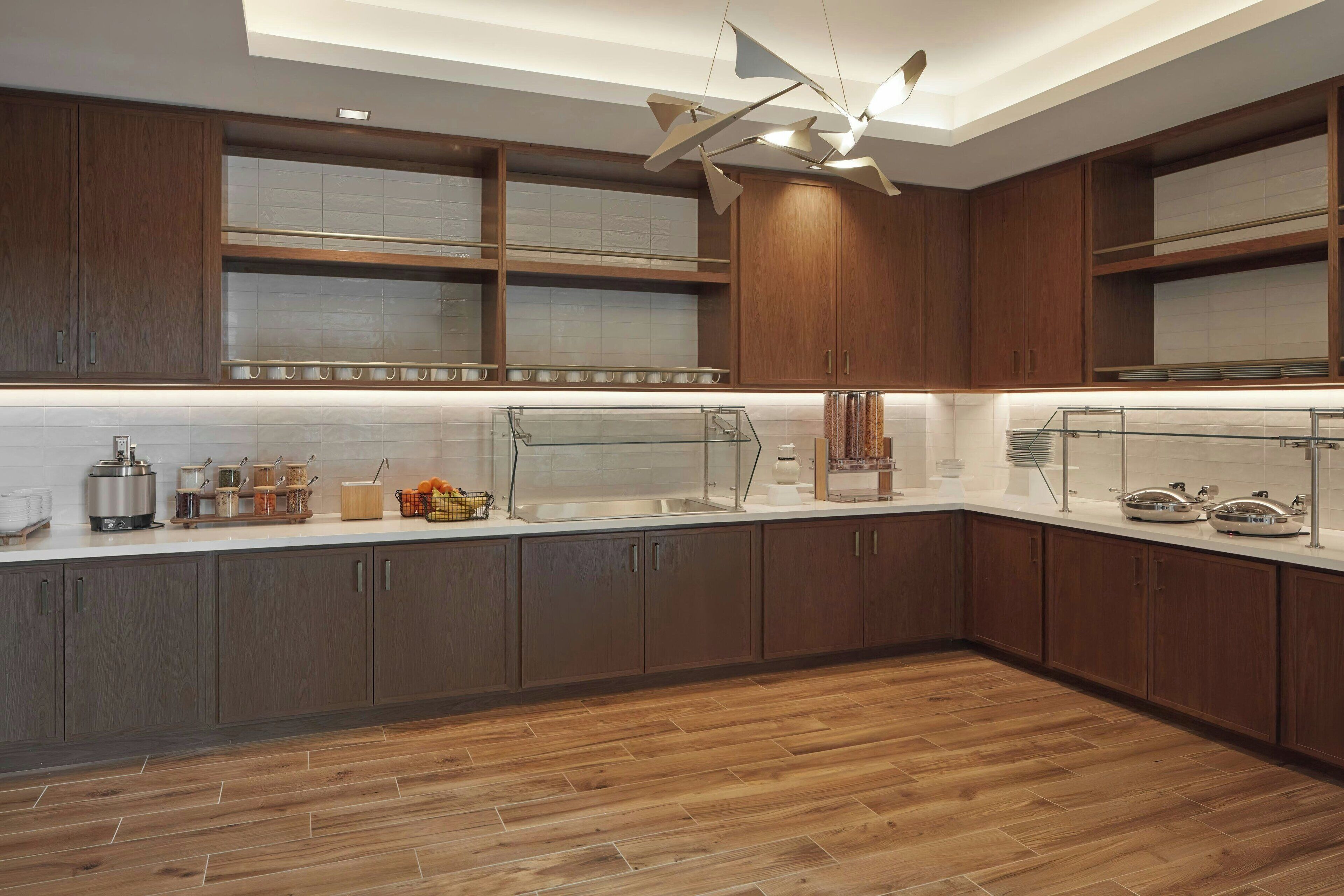 A modern kitchen with wooden cabinets, a glass countertop, and a ceiling fan.