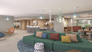 Een moderne hotelentree met een groene bank, meerdere zithoeken en moderne verlichtingsarmaturen.