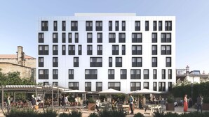 Een modern gebouw met meerdere verdiepingen en een binnentuin met terras.