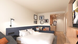 Een moderne hotelkamer met een groot bed, een bureau met een laptop, een stoel en een bank.