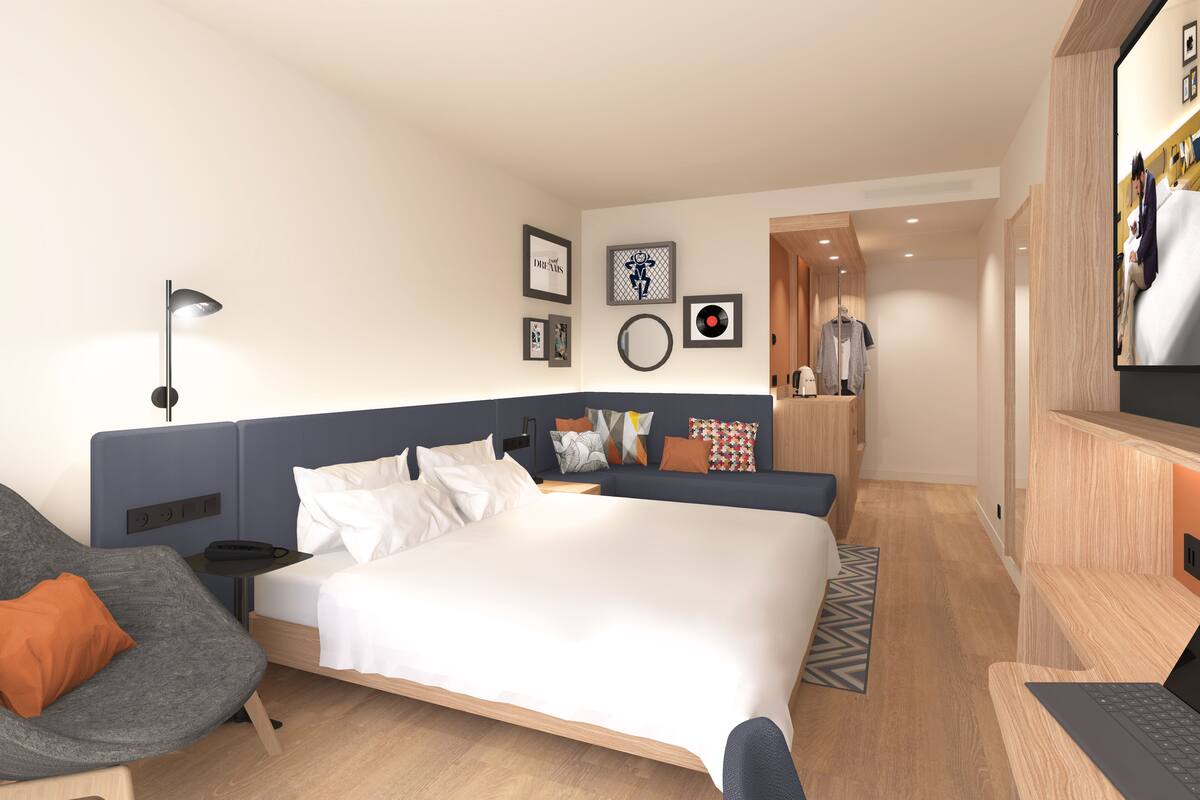 Een moderne hotelkamer met een groot bed, een bureau met een laptop, een stoel en een bank.