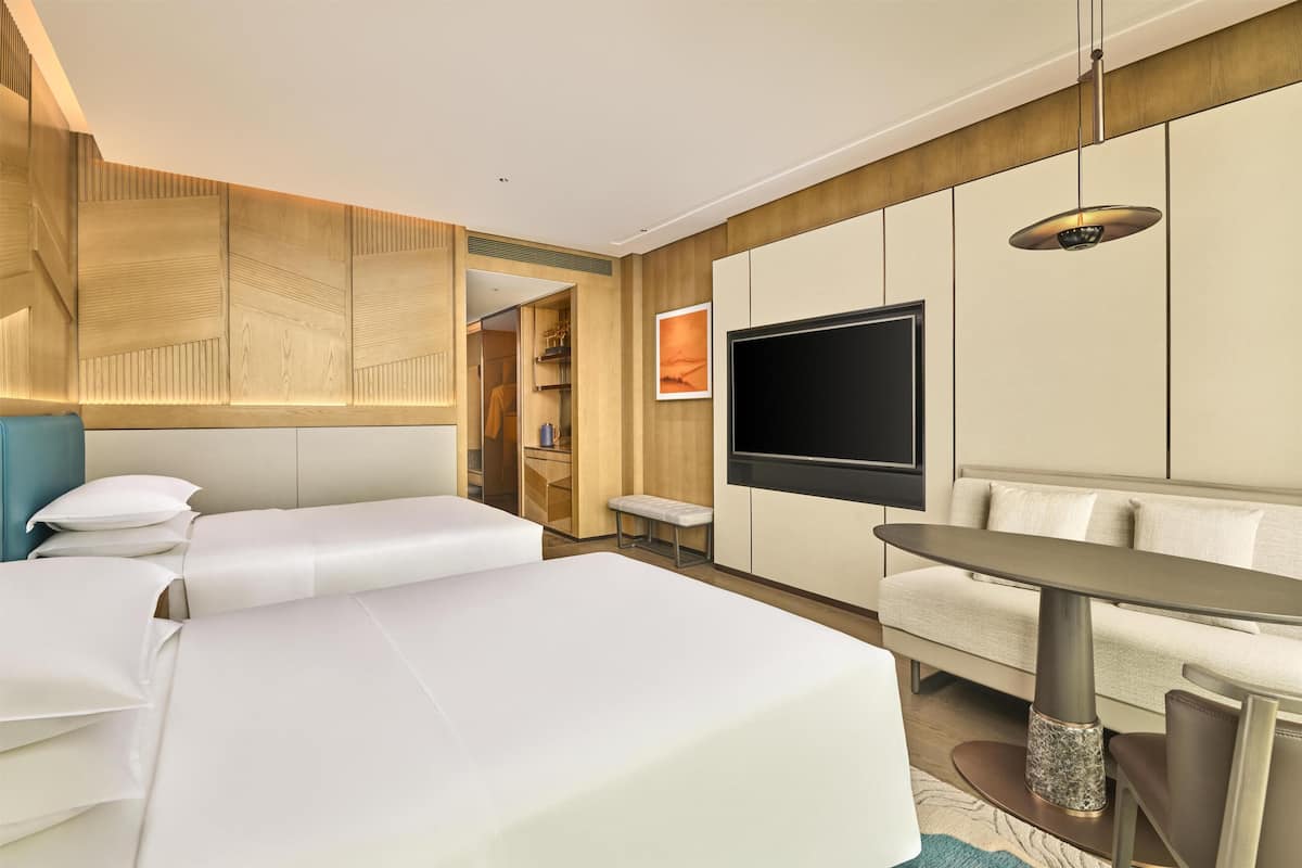 A hotel room with a bed, a sofa, a TV, and a dining table.