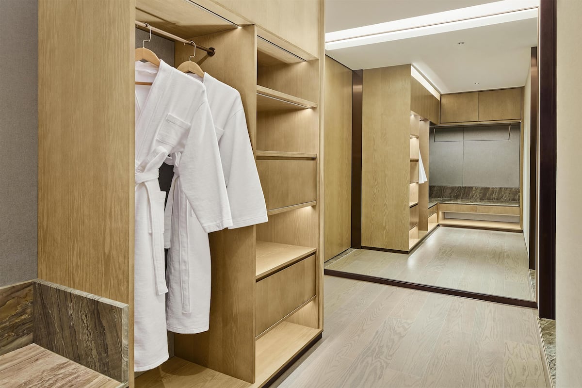 A modern bathroom with a wooden vanity, a mirror, and a shower area.