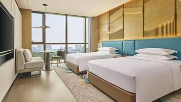 A hotel room with two beds, a sofa, a small table, and a city view.