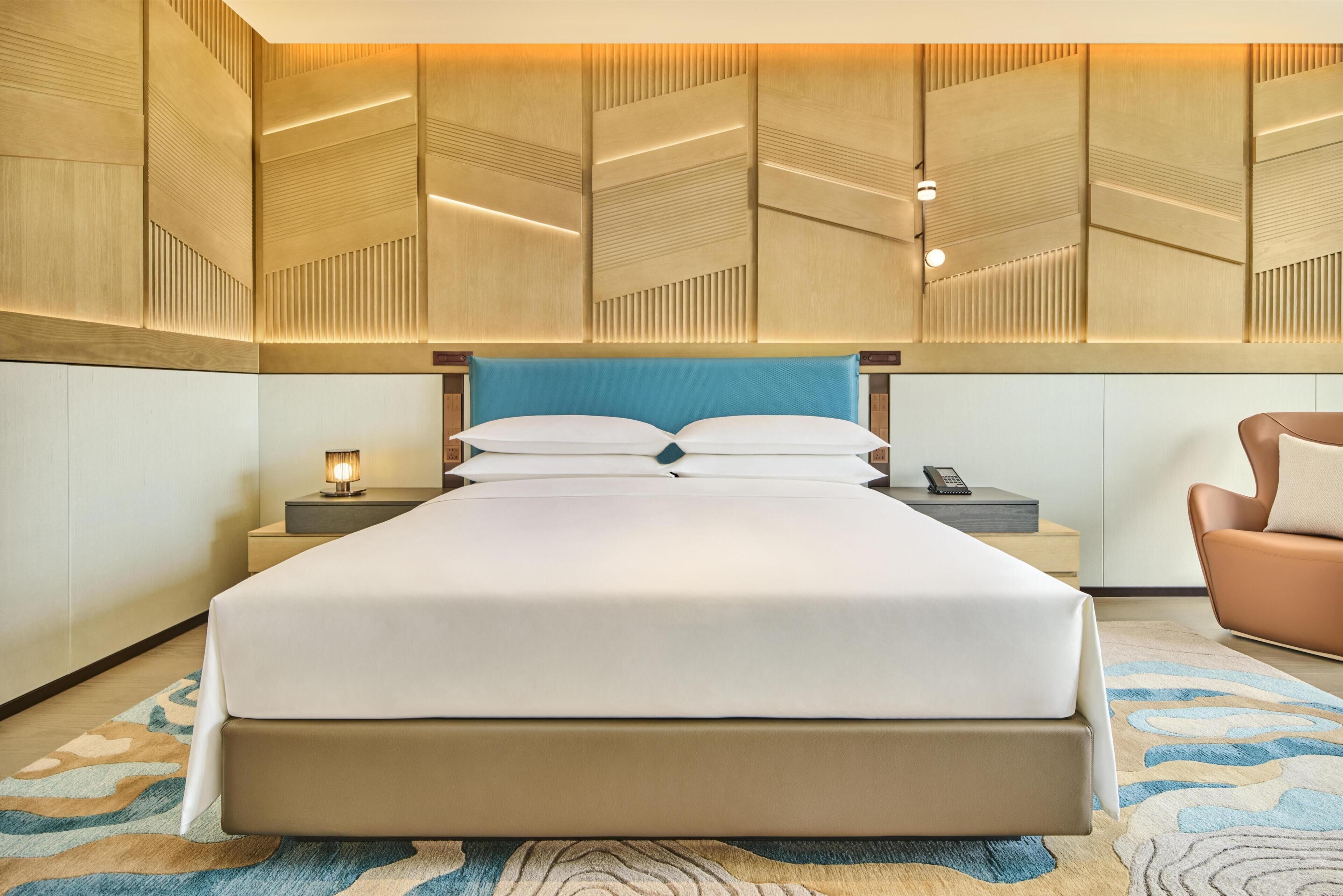 A hotel room with a large bed, bedside tables, a nightstand, a lamp, and a chair.