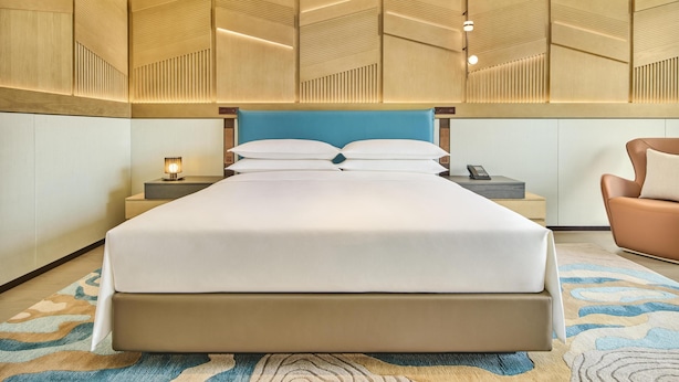 Ein Hotelzimmer mit einem großen Bett, Nachttischen, einer Lampe und einem Sessel.