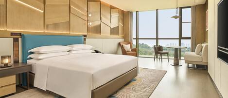 A modern hotel room with a large bed, a desk, a chair, a TV, and a view of the city.