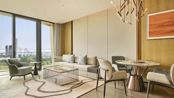 Un salon moderne avec un canapé, des fauteuils, une table basse et une vue sur le paysage urbain grâce à de grandes fenêtres.