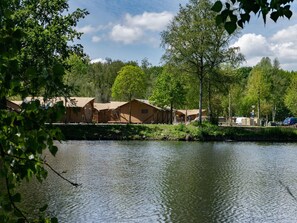 A lakeside campsite with several wooden cabins, a dock, and a clear view of the water.