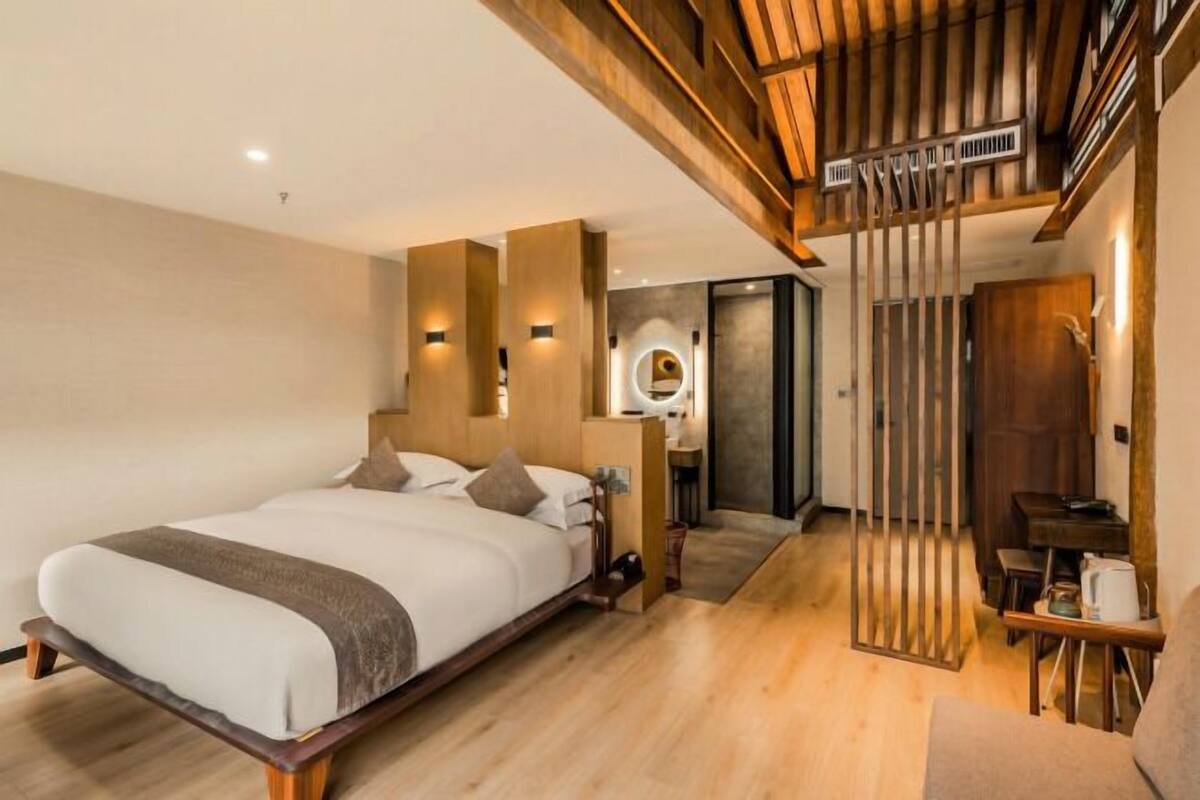Una habitación de hotel moderna con una cama de madera, un escritorio y una escalera.