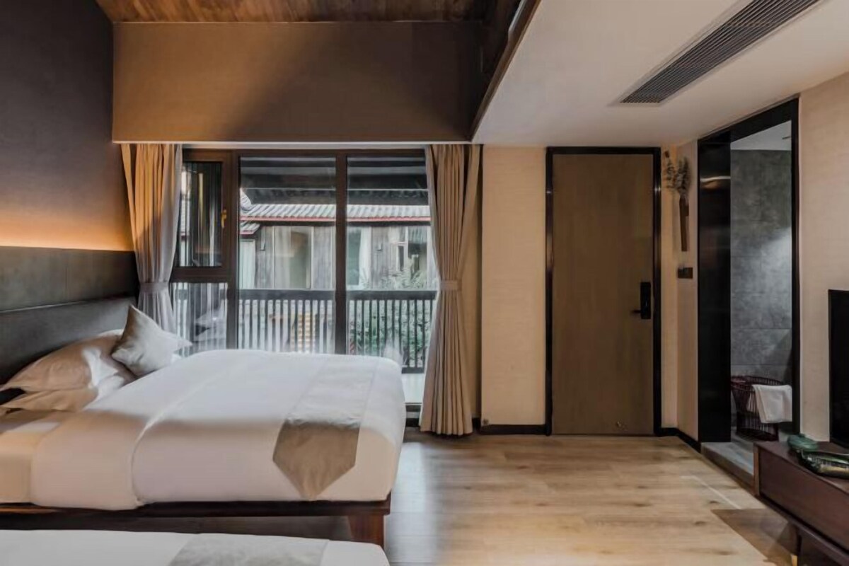 A hotel room with a bed, a TV, a wardrobe, and a balcony with a view.