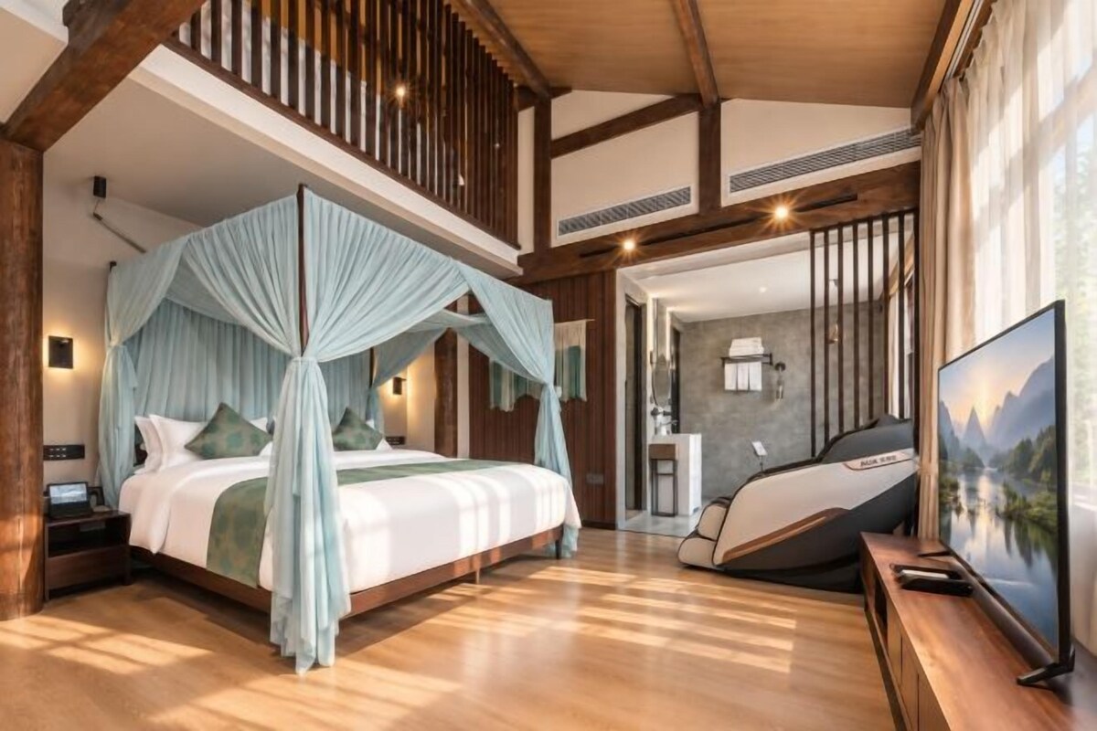 A bedroom with a four-poster bed, a television, and a desk with a chair.
