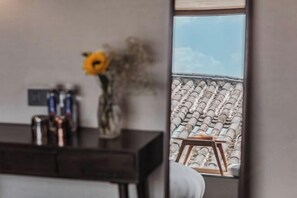 A room with a view of a tiled roof, a small wooden stool, and a vase with flowers on a dark-colored piece of furniture. - Jingli Yisu Inn (Lijiang)
